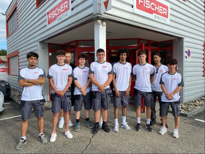 Un groupe de jeunes collaborateurs devant le bâtiment de Fischer Electric
