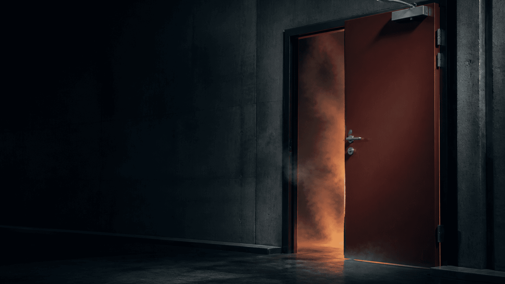 A fire-rated steel door partly open with smoke passing through