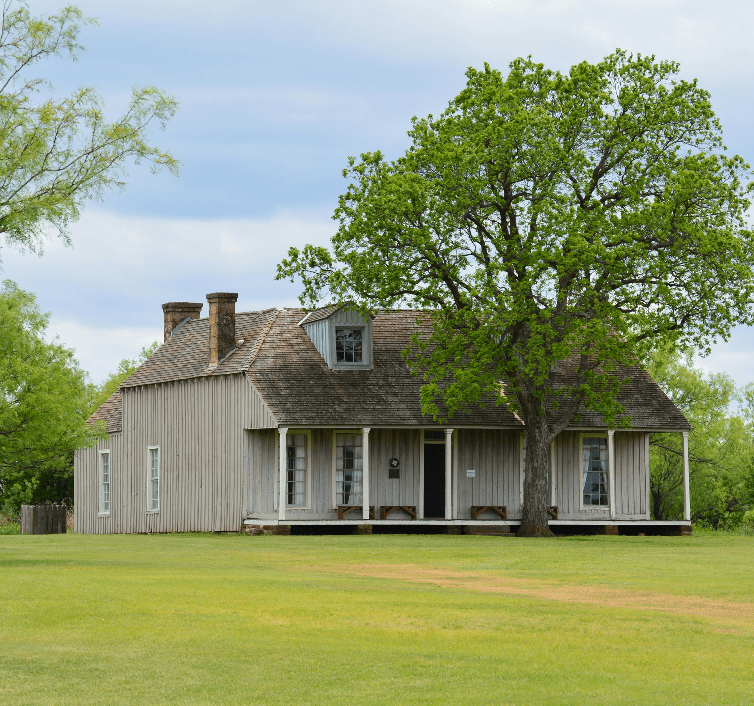 A modern house with a large lawn and a partly cloudy sky.