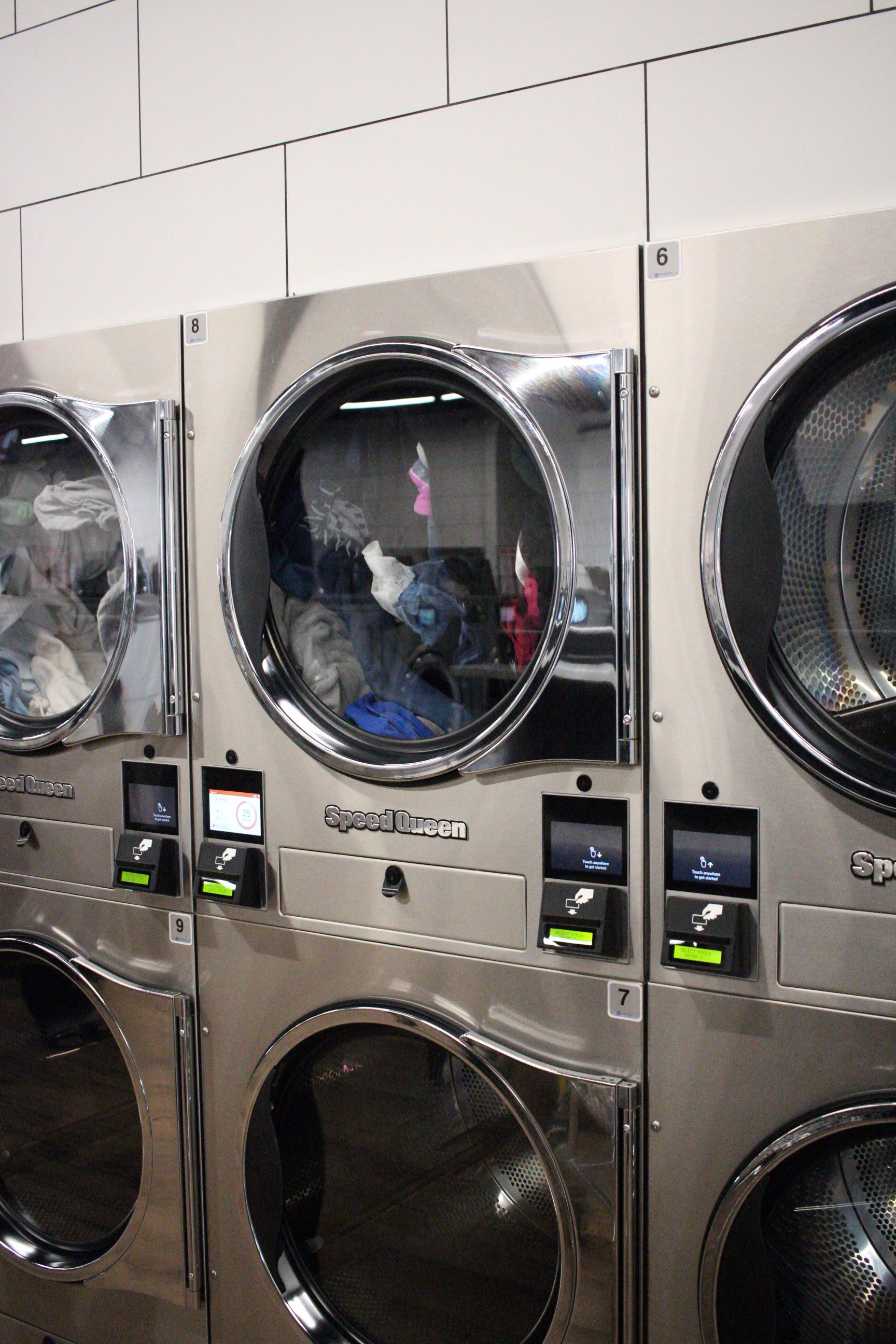 Washing machines in local laundromat spinning with clothes inside