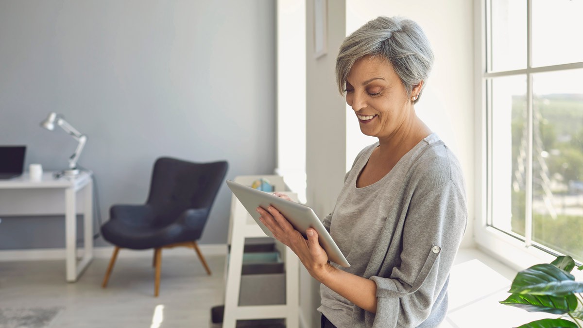 A woman holding a tablet during an online call while standing in her office 