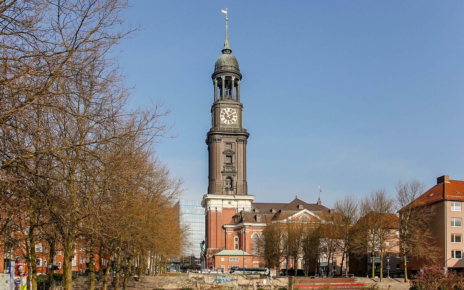 St. Michael's Church tower in Hamburg, view from a tree-lined street.