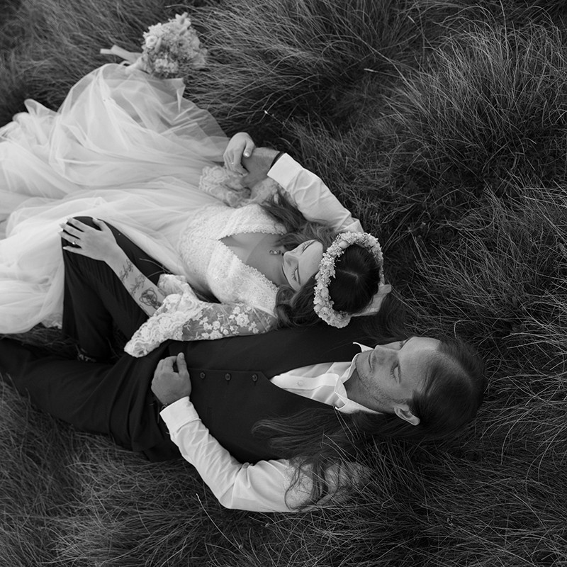Bride and groom standing holding each other with steps and wooden gate behind