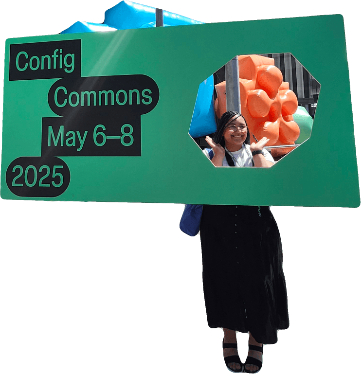 Malaika joyfully poses behind a large green cutout sign promoting "Config Commons" scheduled for May 6-8, 2025, with colorful, abstract shapes in the background.