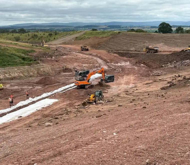 Excavators and dump trucks carrying out bulk earthworks and drainage installation on a large-scale civil engineering infrastructure project.