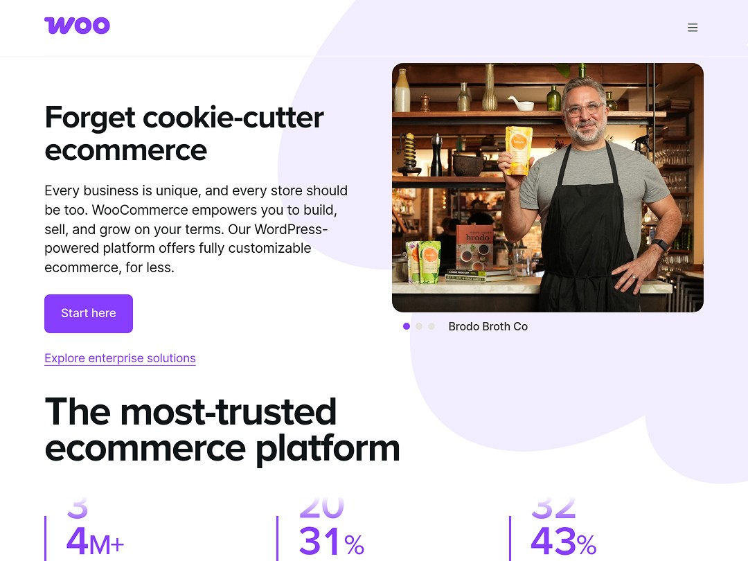 Man in apron holding Brodo Broth Co products behind a counter in a warm, rustic kitchen setting