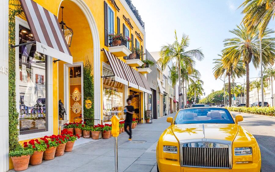 Gele luxe auto geparkeerd op Rodeo Drive, Beverly Hills, met palmbomen en chique winkels.