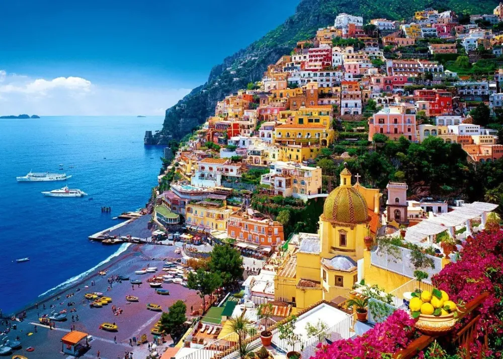 Positano seen from the water, with its church dome, colourful houses and beach umbrellas.