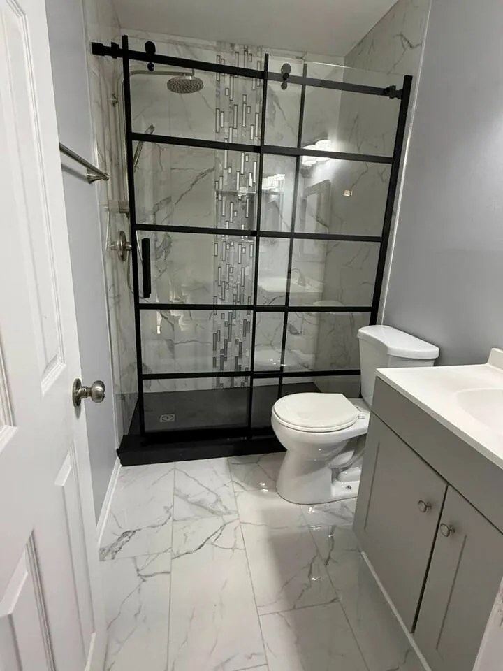 Renovated bathroom with a black-grid glass shower and marble-look tile
