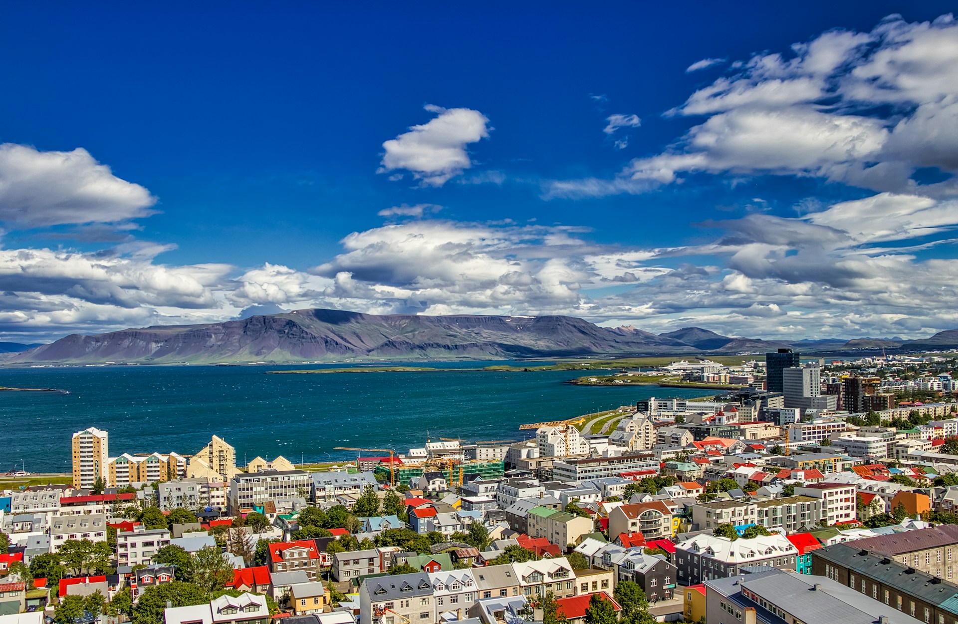 Panoramic view of Reykjavík skyline overlooking Faxaflói Bay and Mount Esja on a clear day.
