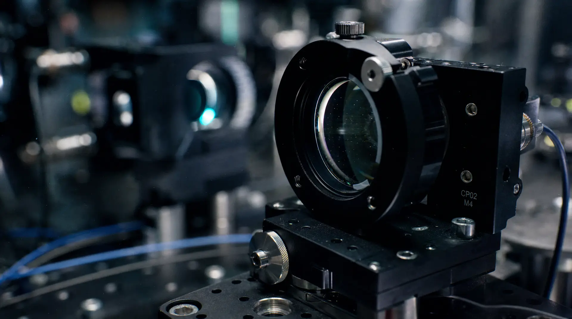 A close-up of a precision camera module with lens and mounting hardware on a robotic platform, with blurred lab equipment in the background, robotics branding focus.