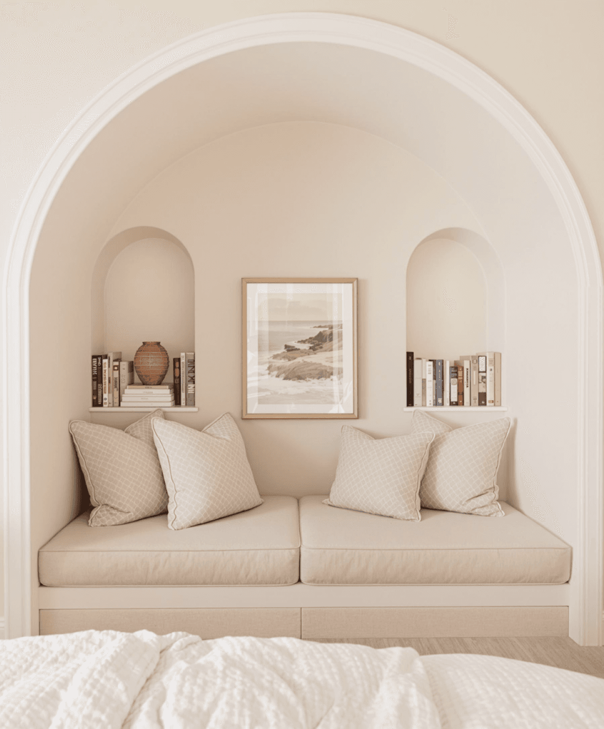 Cozy arched reading nook with soft cushions, bookshelves, and framed wall art.