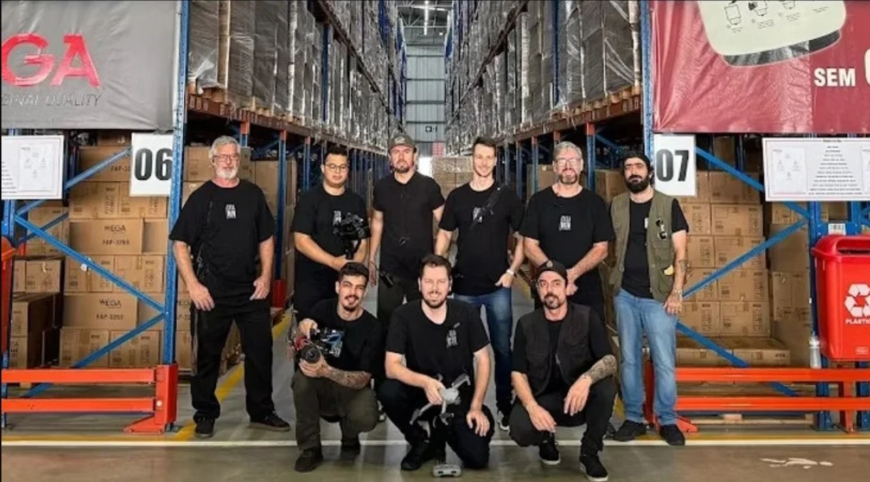 Equipe da Casa Oito reunida em corredor do centro de distribuição da Wega Motors