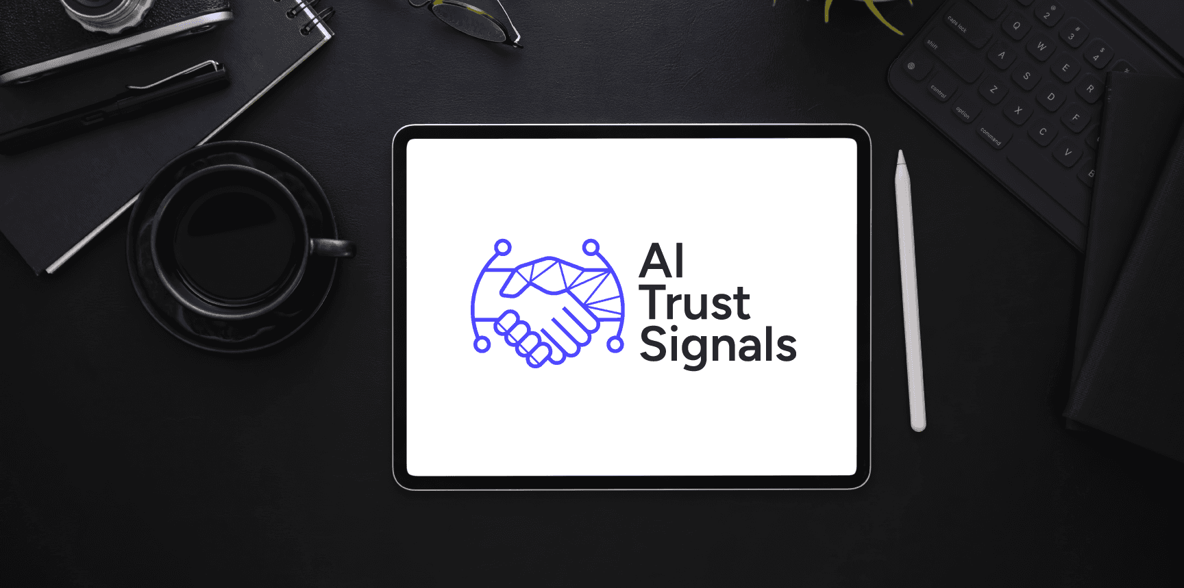AI Trust Signals logo, featuring a digital handshake icon, displayed on an iPad screen surrounded by professional dark desk accessories, including a coffee cup, keyboard, and glasses.