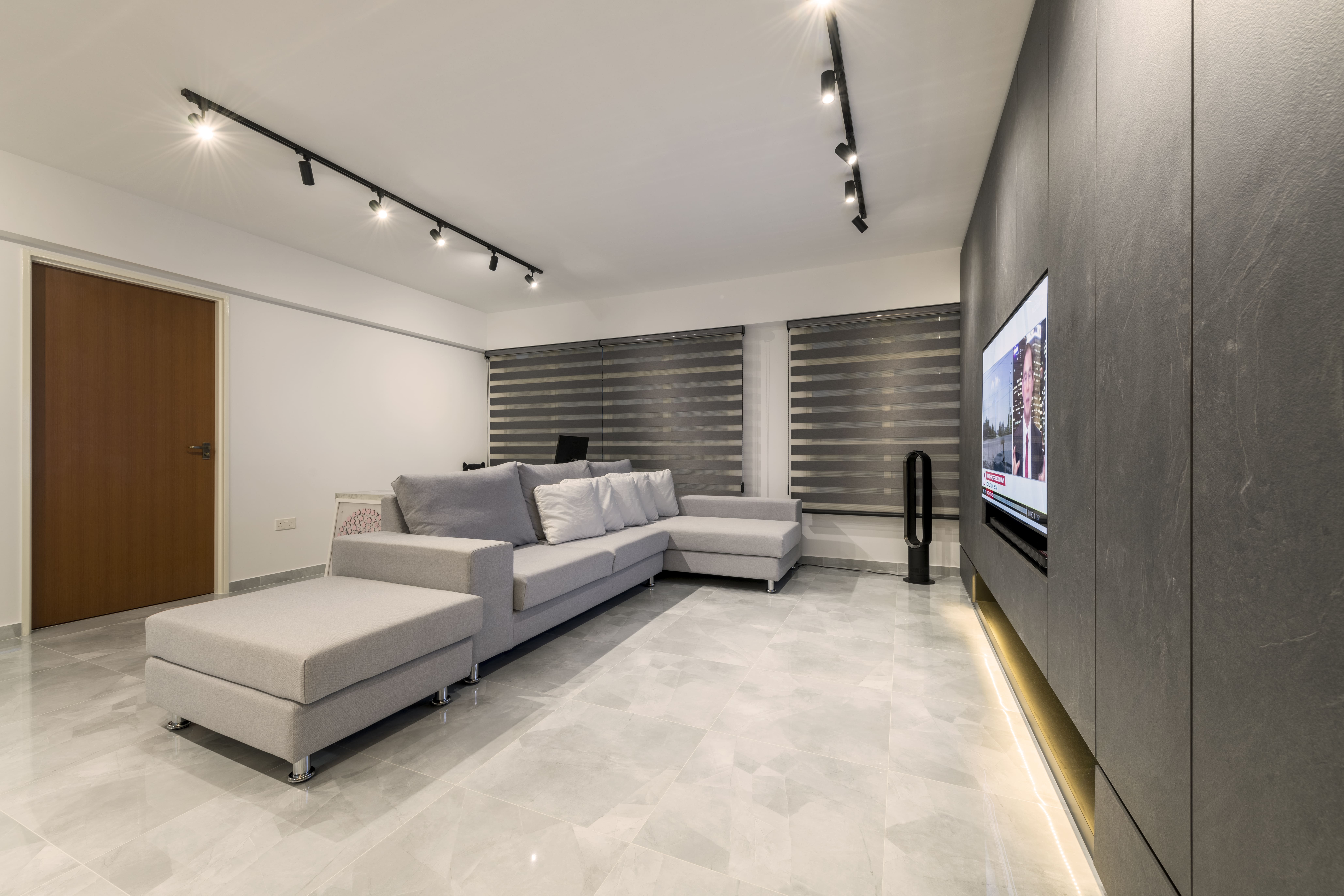 An alternate view of the living room reveals layered blinds, soft grey tones, and track lighting that ensures even illumination across the entire space.