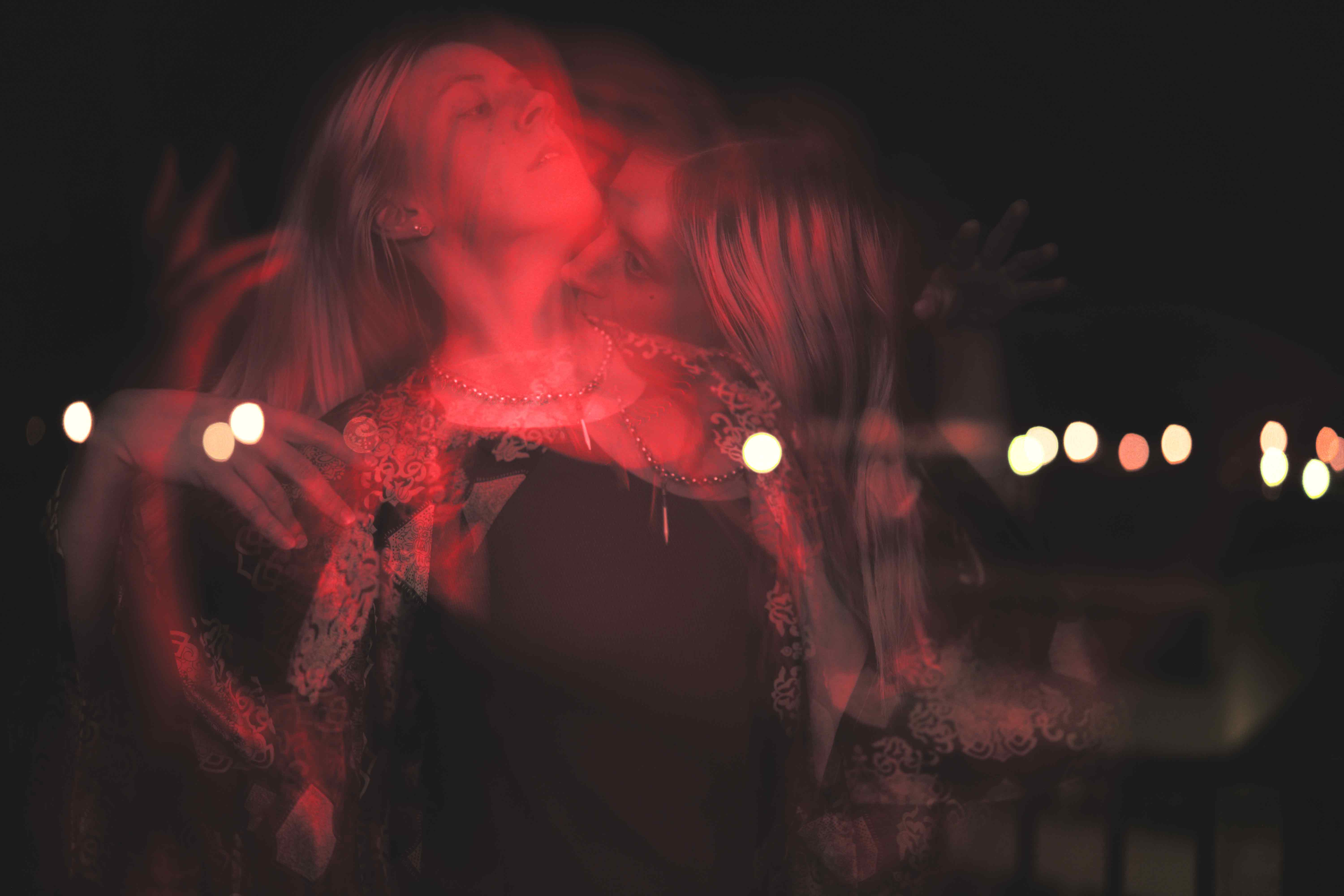 Photographie de portrait créative avec plusieurs déclenchements de flash laissant paraître un effet de filé couplé à plusieurs immobilisations d'une femme bougeant avec élégance dans une lueur rouge