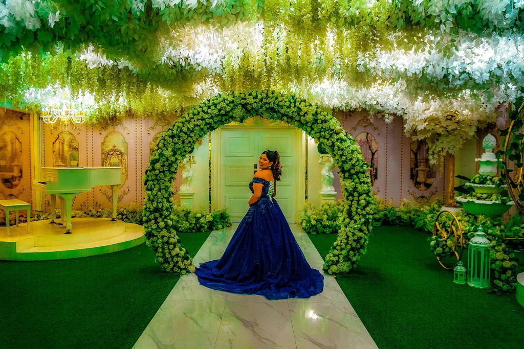 Debutante in a navy ballgown under the garden arch at Celestia Hall