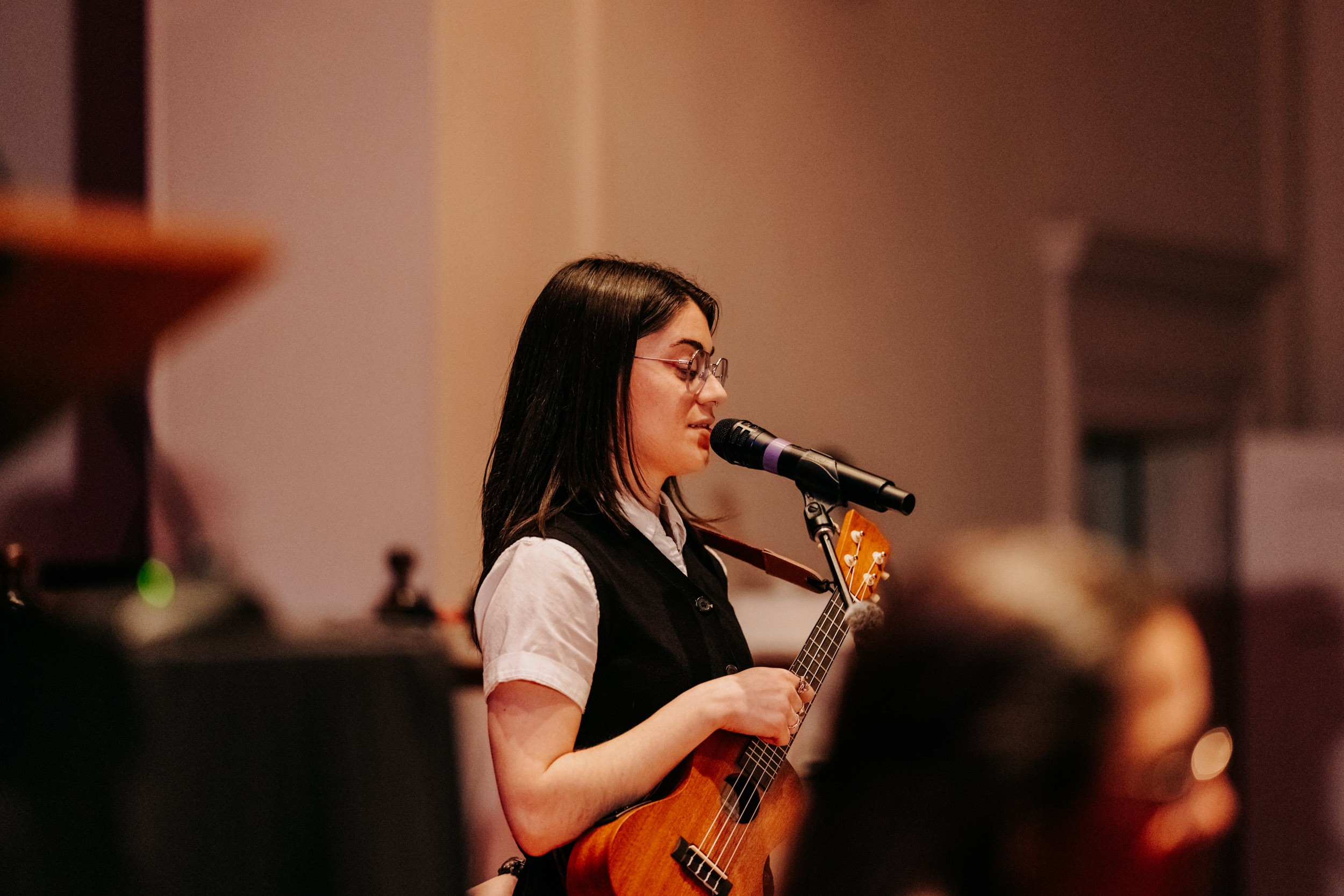 Performer singing and playing ukulele at the Queer Open Mic (QOM) hosted by be; community in Bridgewater, Massachusetts