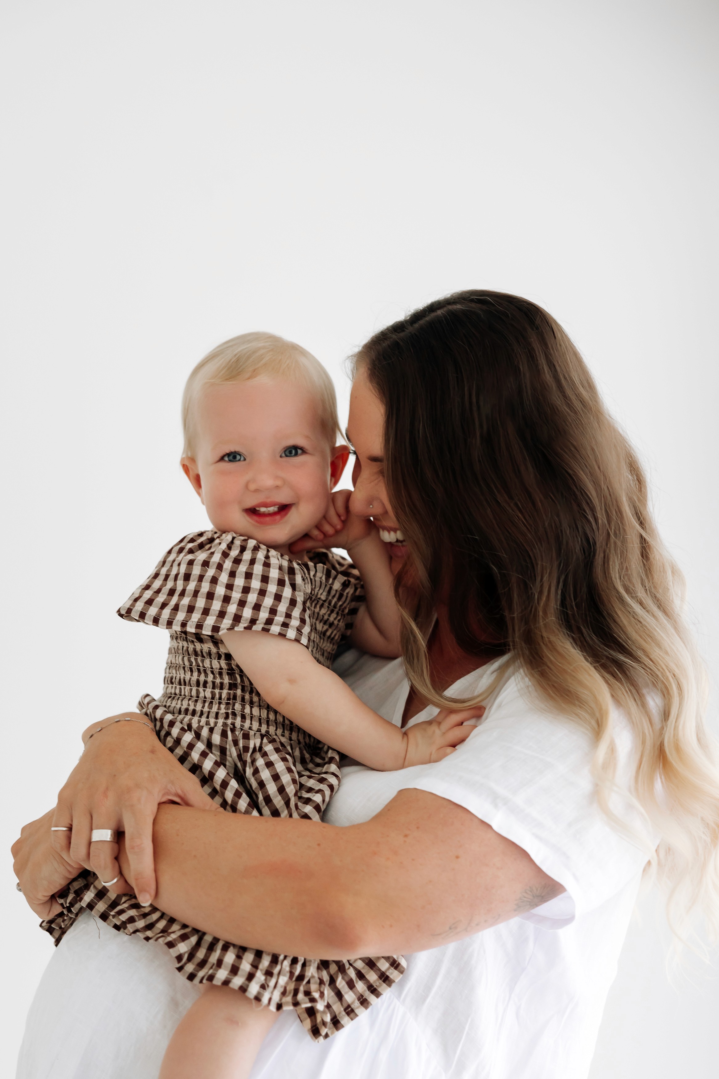 Mother and daughter embracing in a soft natural light maternity studio portrait session in Mackay