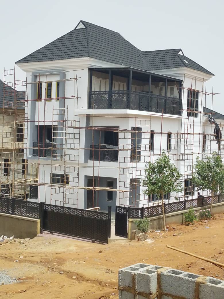 A modern white SUV is parked in a stylish driveway under a sleek carport. A woman in business attire walks towards the vehicle, conveying a professional tone.