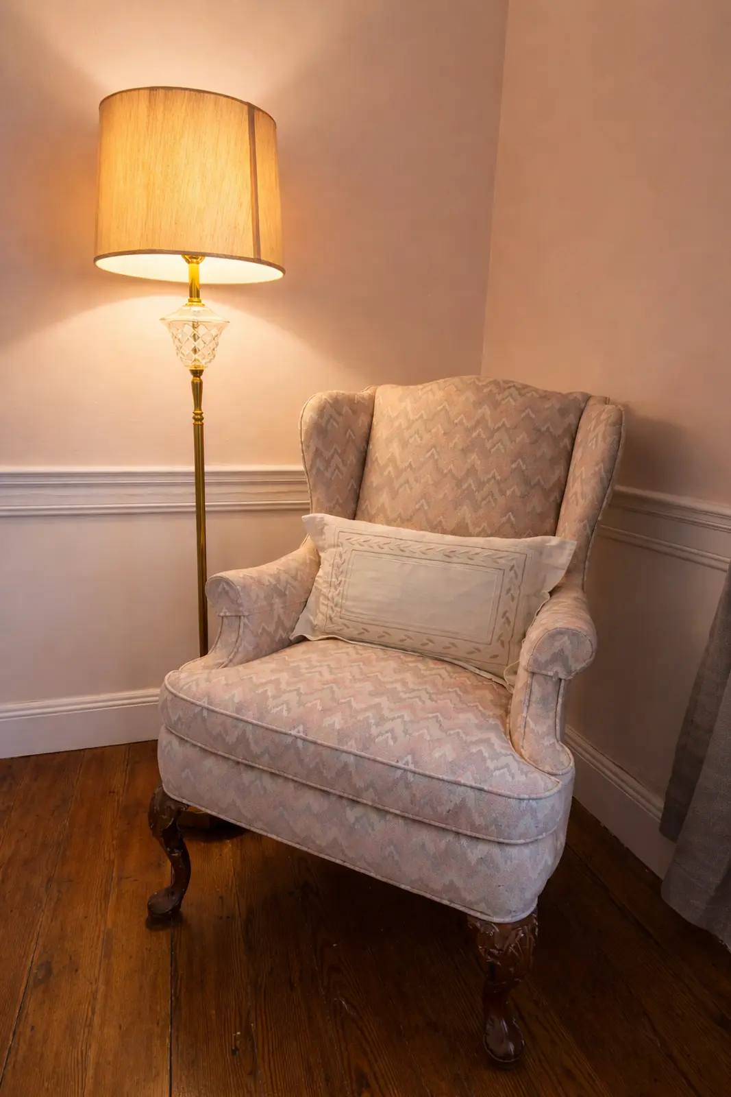 Patterned armchair and lit floor lamp in a cozy corner.