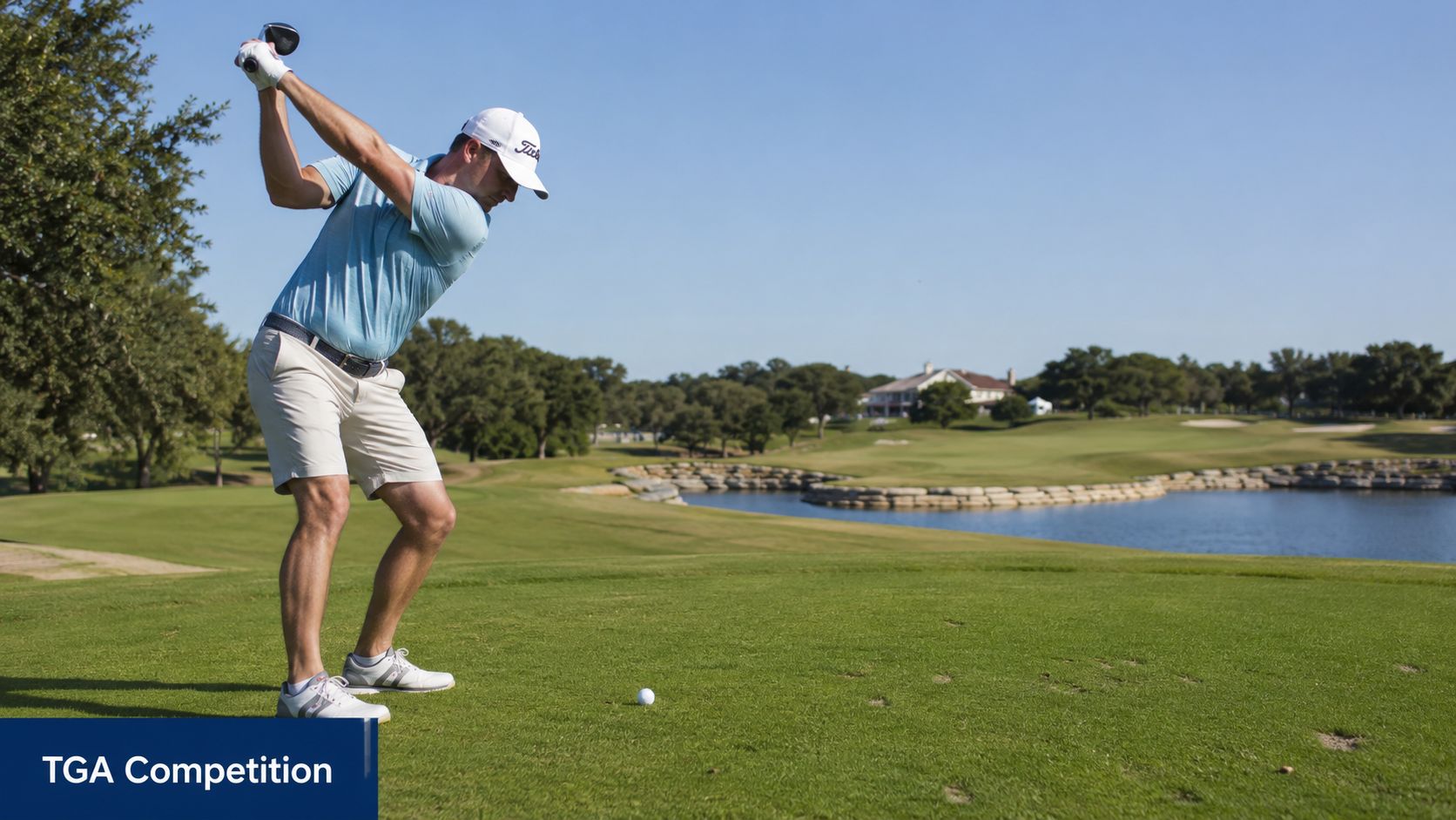 A professional golfer in a blue shirt and khaki shorts swinging a club at a golf course.