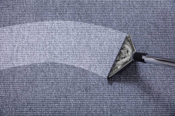 person holding blue textile near clear glass bottle