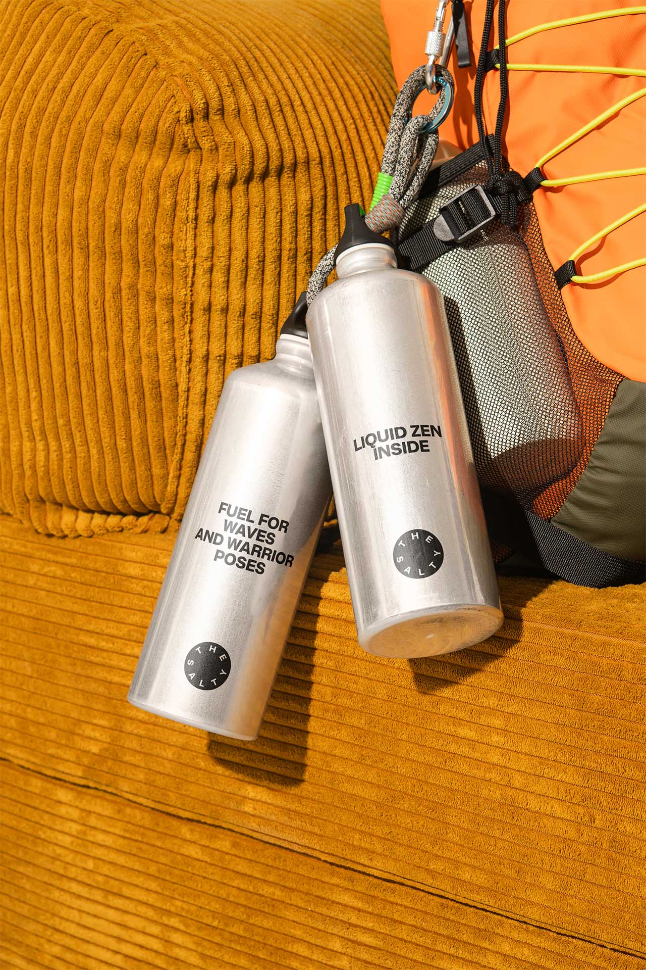 Titanium water bottles branded with The Salty logo and inspirational quotes.