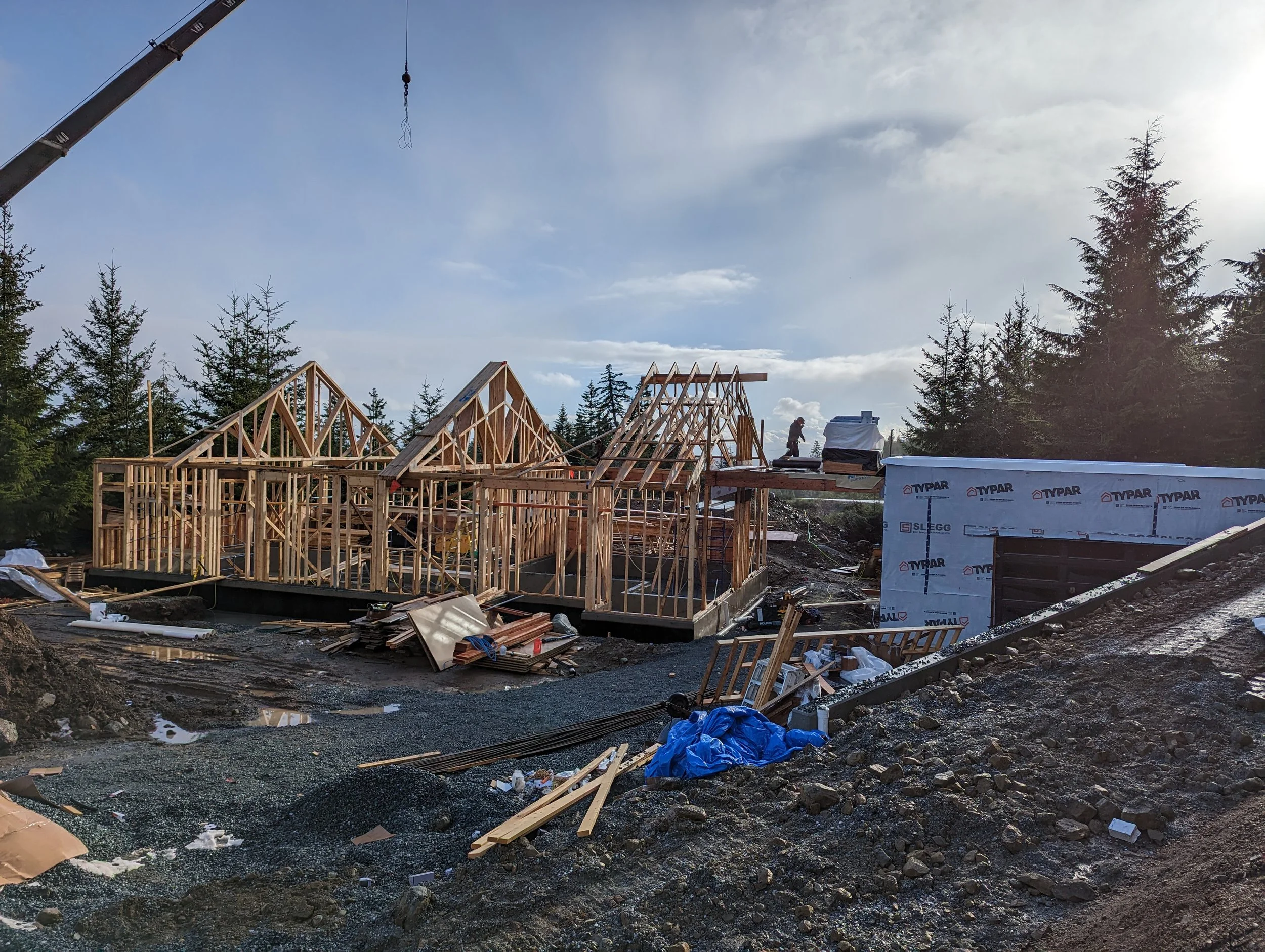 Modern two-story home with large glass windows, warmly lit interiors, and a balcony. Surrounded by trees and a manicured lawn at dusk. Cozy ambiance.