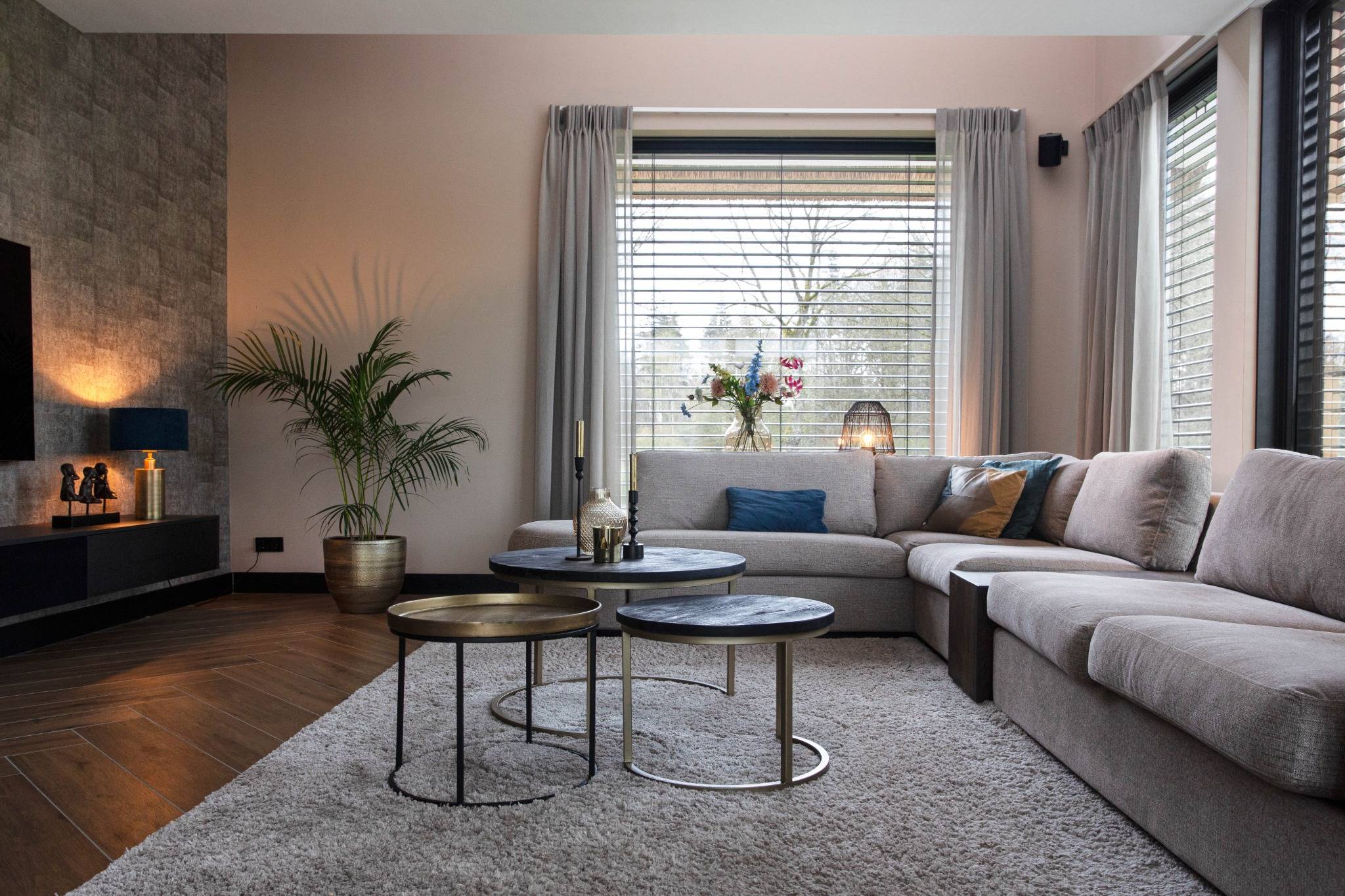 Woonkamer met grote hoekbank, warme tinten, houten vloer en rustige styling in een rietgedekte villa.