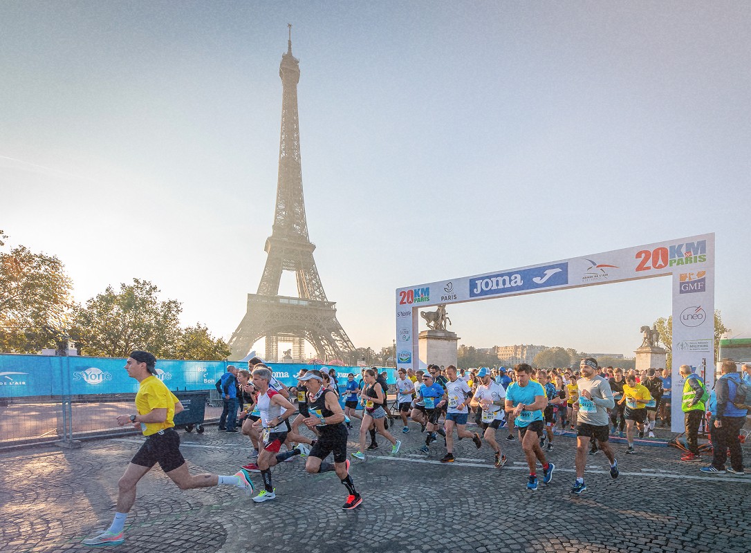 Groupe de personnes en train de participer à une course à pied avec la Tour Eiffel en arrière-plan lors des 20 KM de Paris.