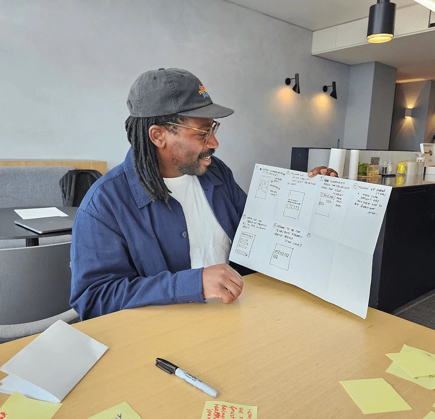 Workshop participant presenting sketched interface ideas on paper.