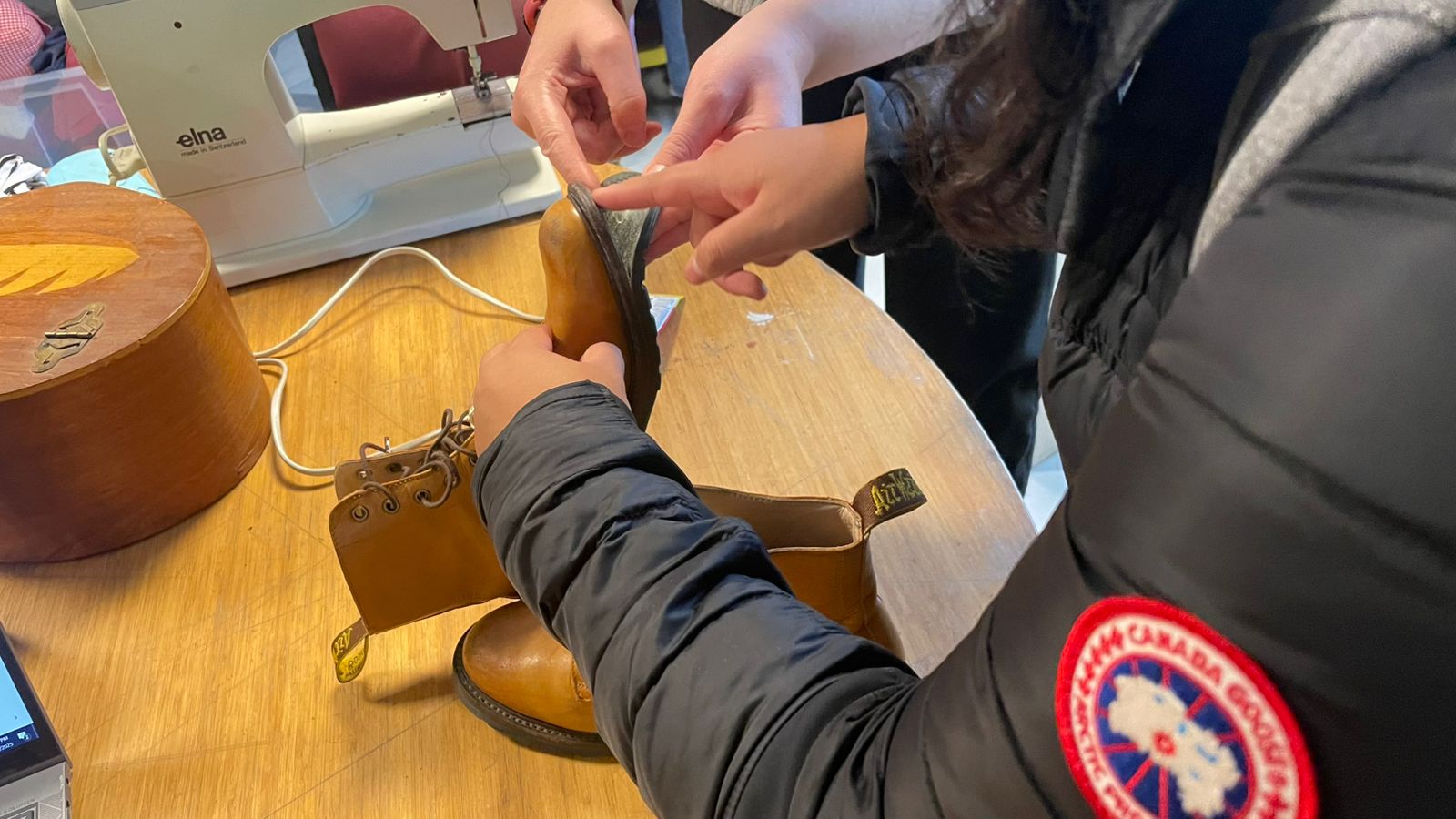 A teammate repairs her worn boots at Riga's Repair Café, experiencing the service the way a visitor would.