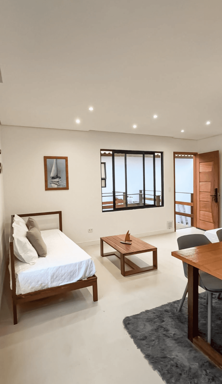 a spacious open-concept layout with a king bed, living area, and ocean beyond full-length windows.