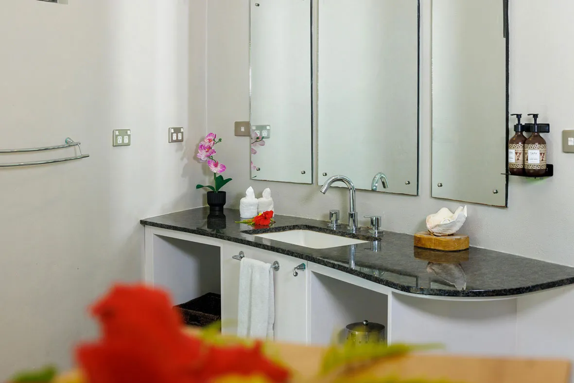 A clean white bathroom with red flowers in a commodore villa at Uprising Beach Resort Fiji