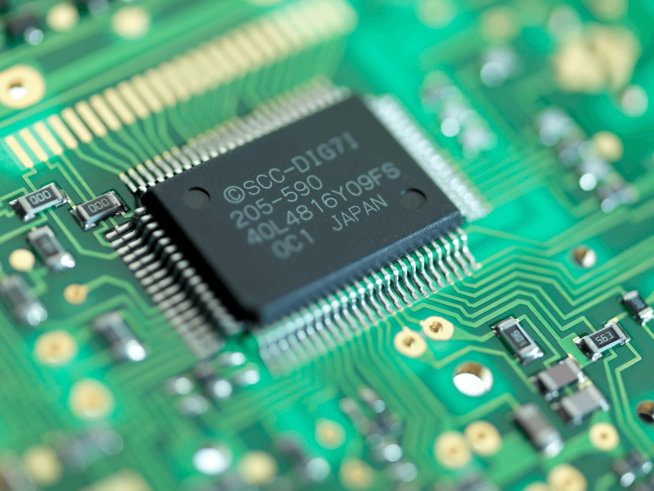 Macro photo of a quad-flat-pack integrated circuit on a green circuit board