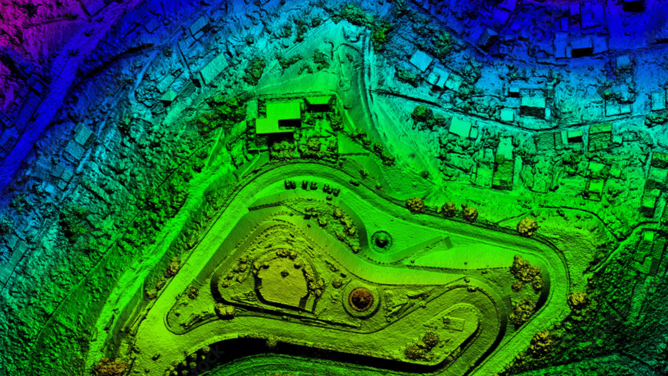 A man stands while two people sit at a table in an office setting, smiling and engaged in conversation. The mood is friendly and collaborative.