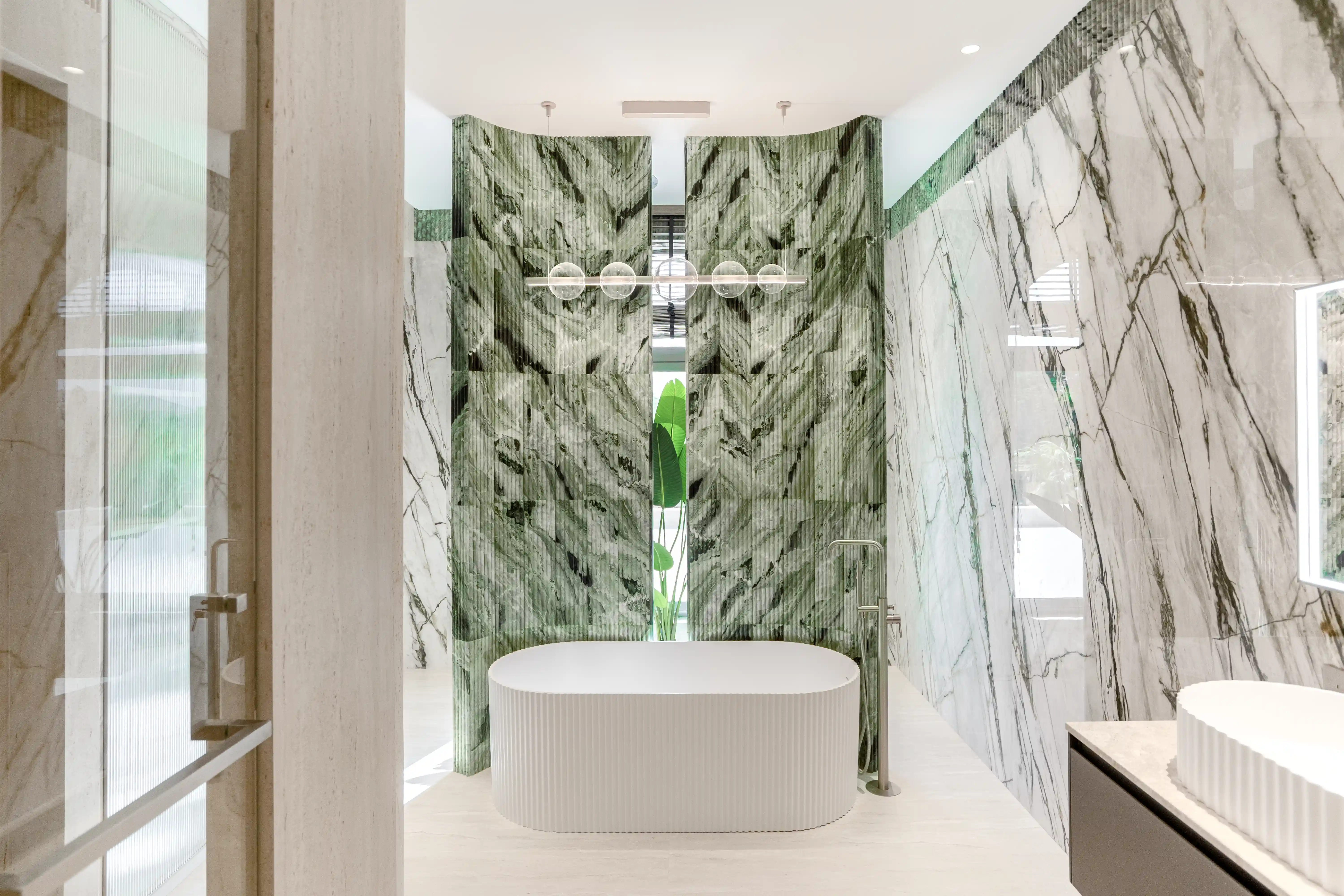 Bathroom with green fluted marbles and a bathtub.
