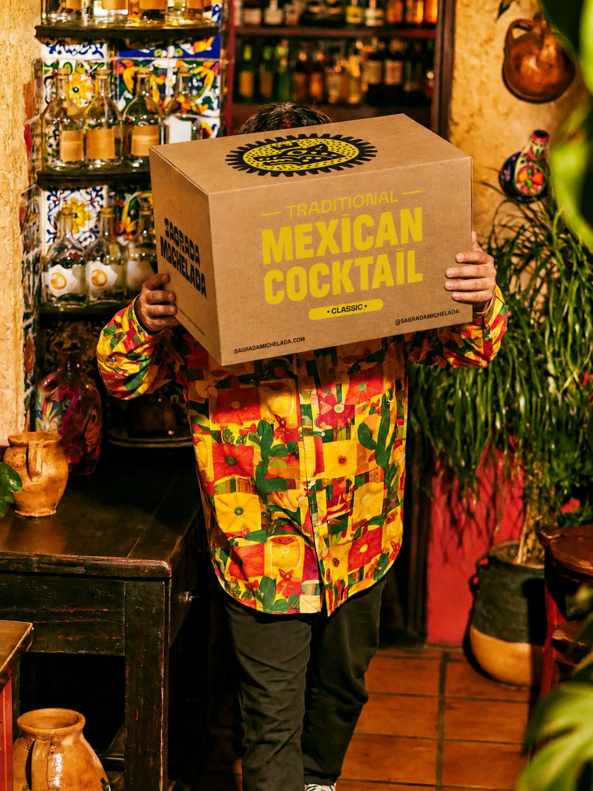 Sagrada Michelada Classic shipping box with yellow crown pattern and printed bottle graphics, e-commerce packaging design