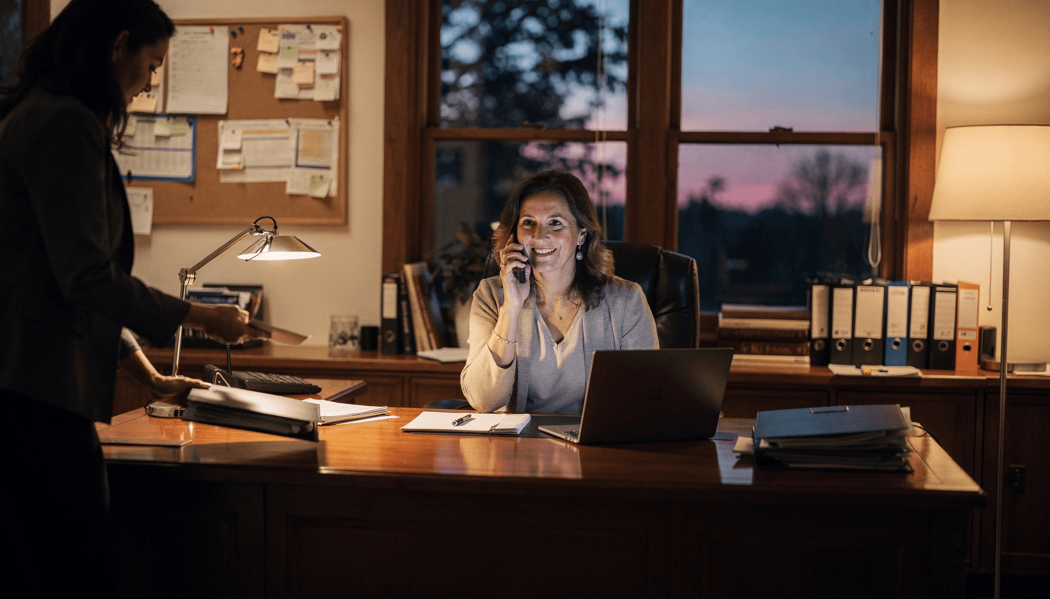 Woman working late at a desk with a laptop and paperwork