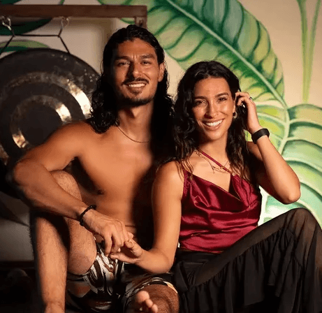 Four friends laughing together outdoors in natural light, dressed in neutral casual outfits.