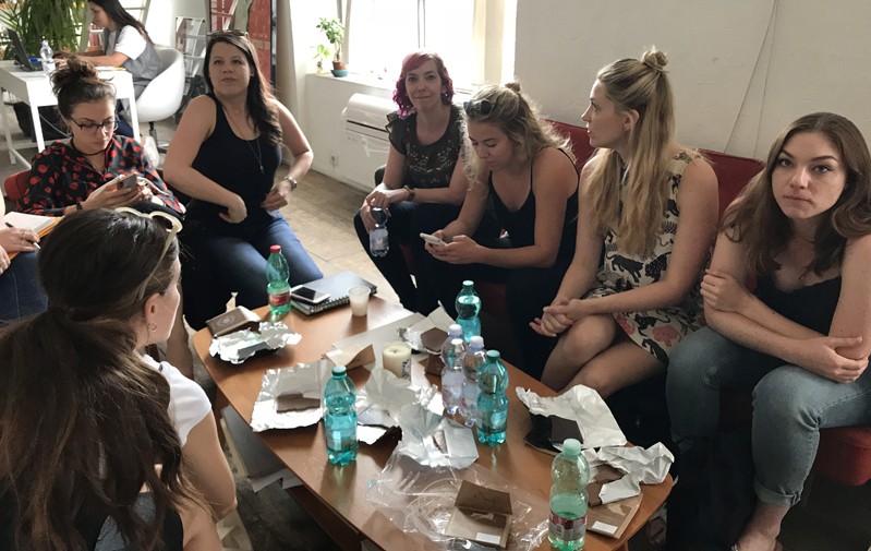 A photo of a group of people sitting on couches around a table.