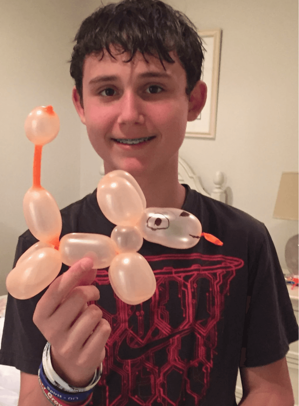 Young Daniel smiling and holding a balloon animal shaped like a dog in a cozy indoor setting