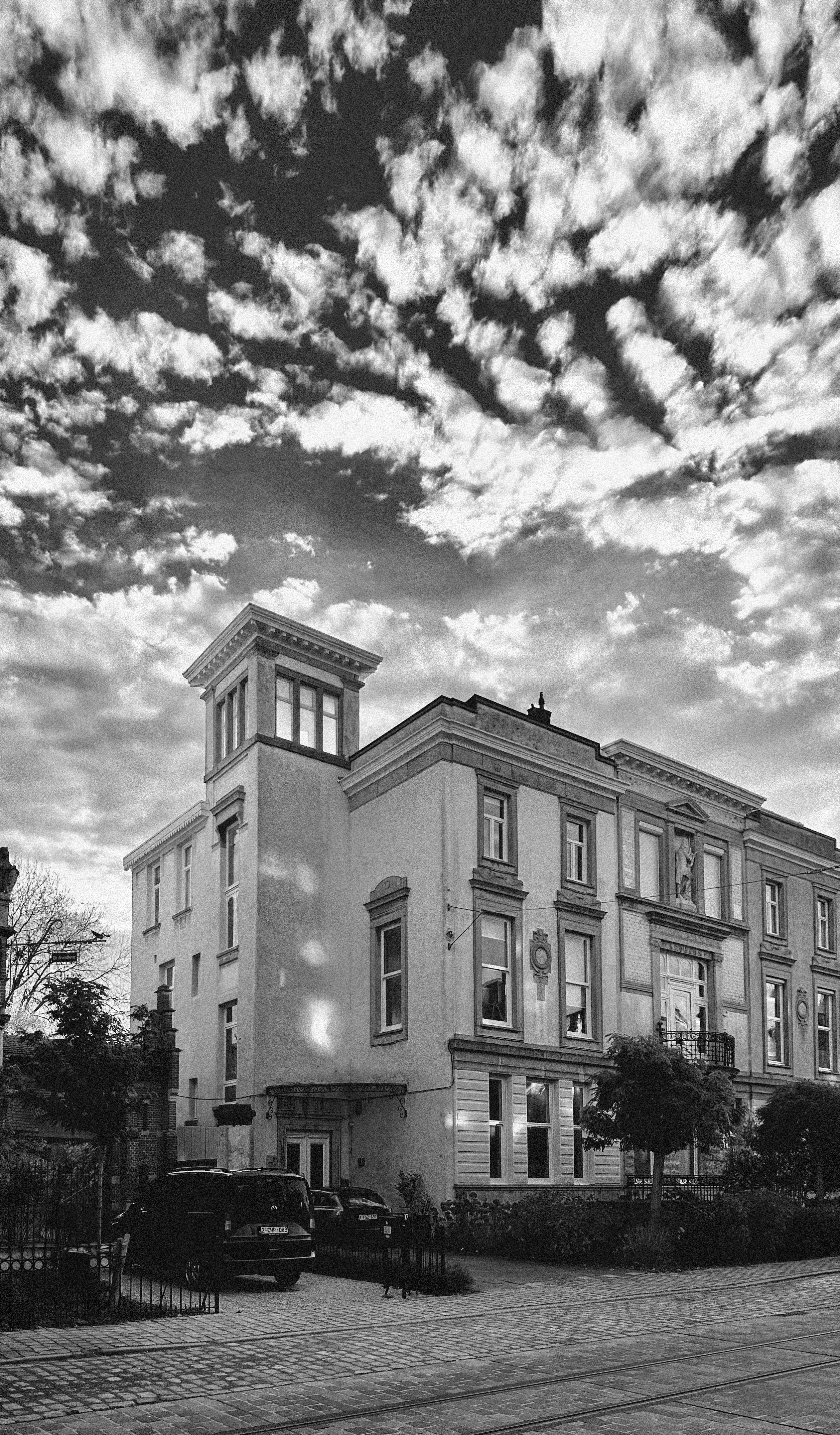 Black and white image of the FRHM office, a large building under a textured cloudy sky.
