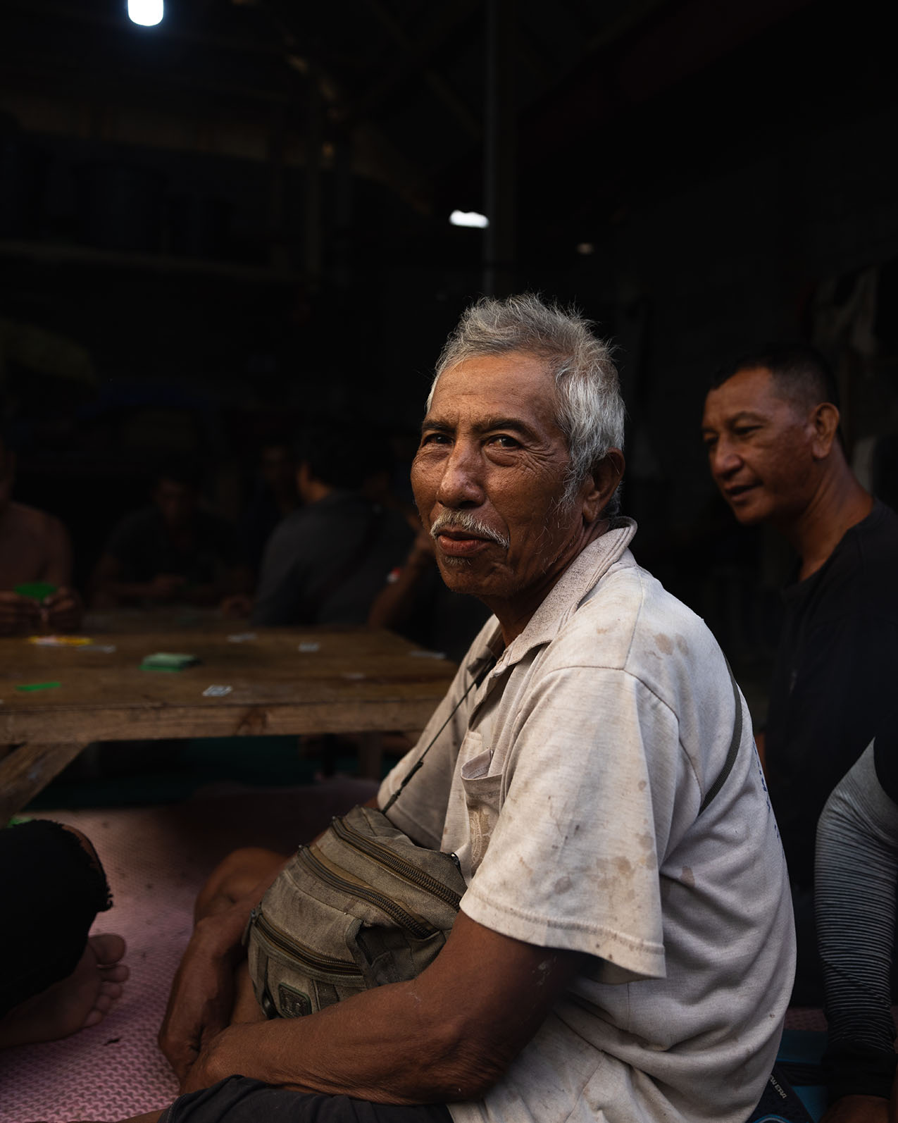 Portrait of an Indonesian man playing cards in a dark building.
