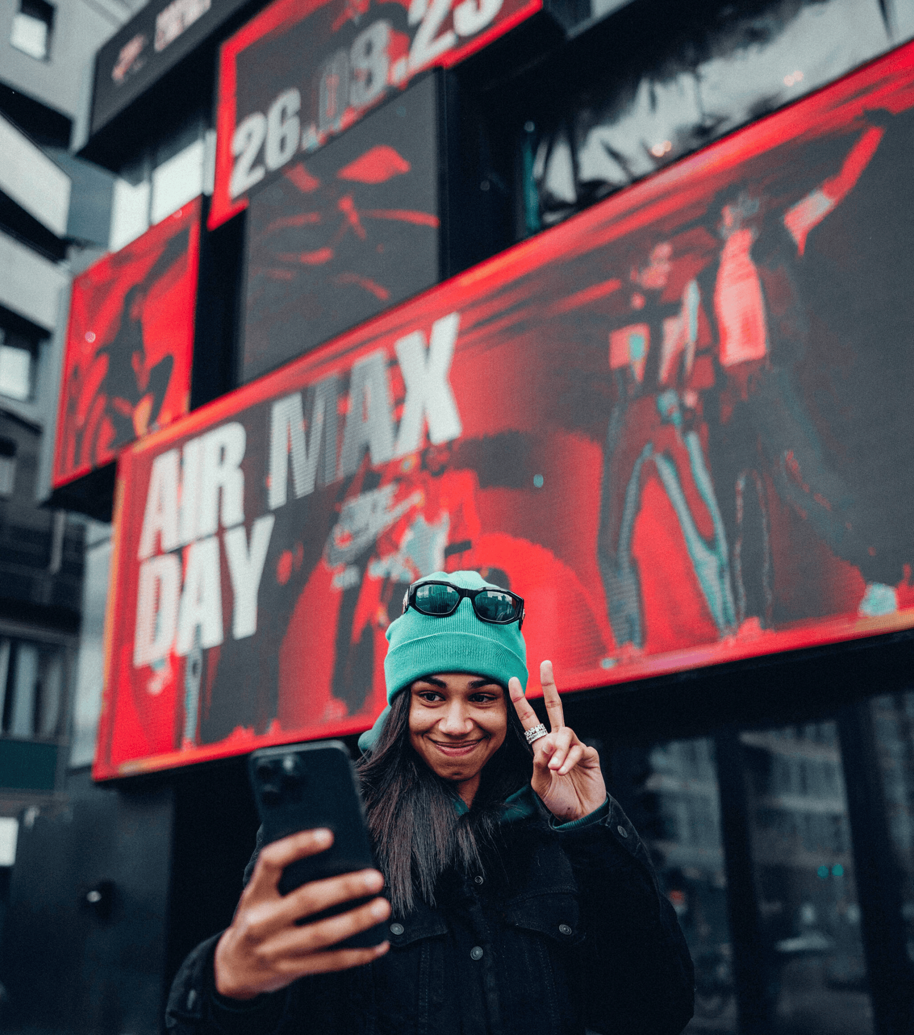 User taking a selfie of her Nike avatar displayed on the massive screens of the building.