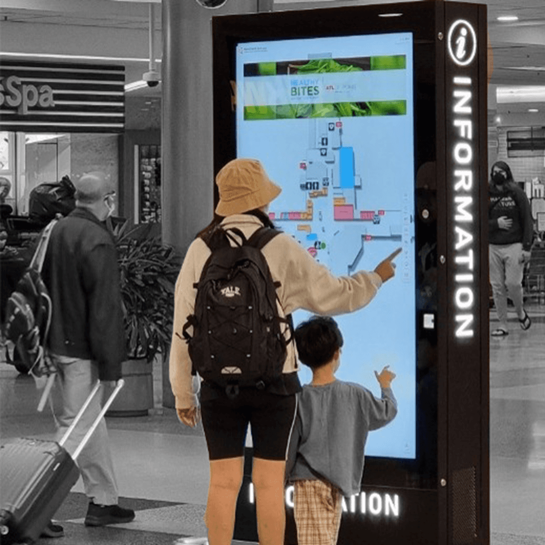 Parent and child using an interactive kiosk in an airport