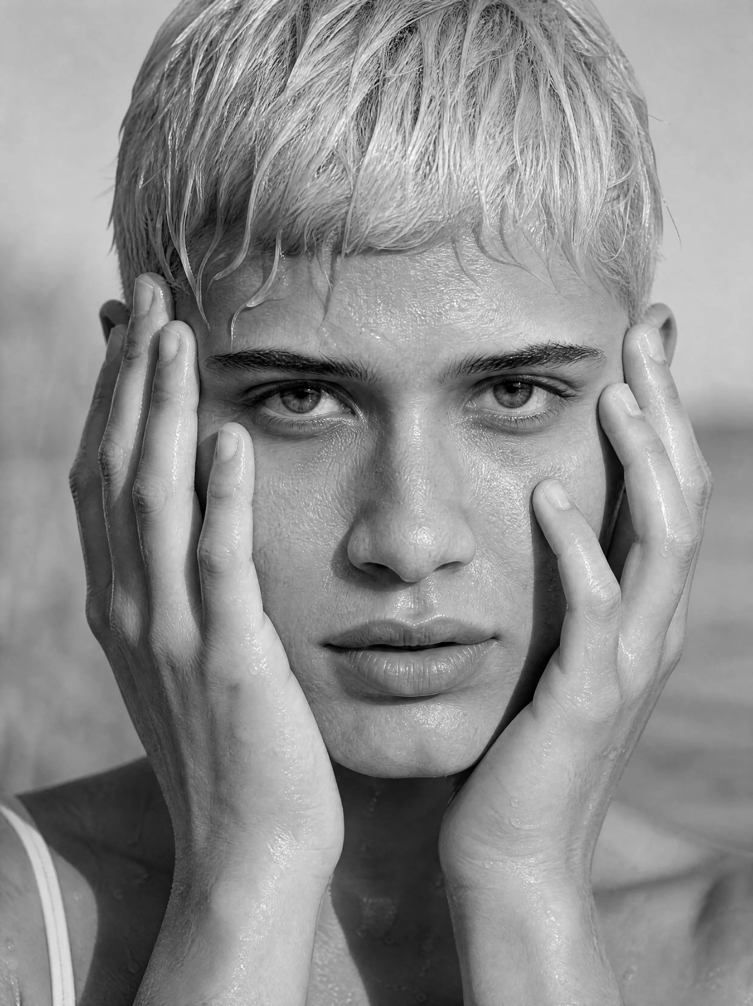 Stella Moreau – Person mit kurzen hellblonden Haaren, die Hände am Gesicht, vor Wasser