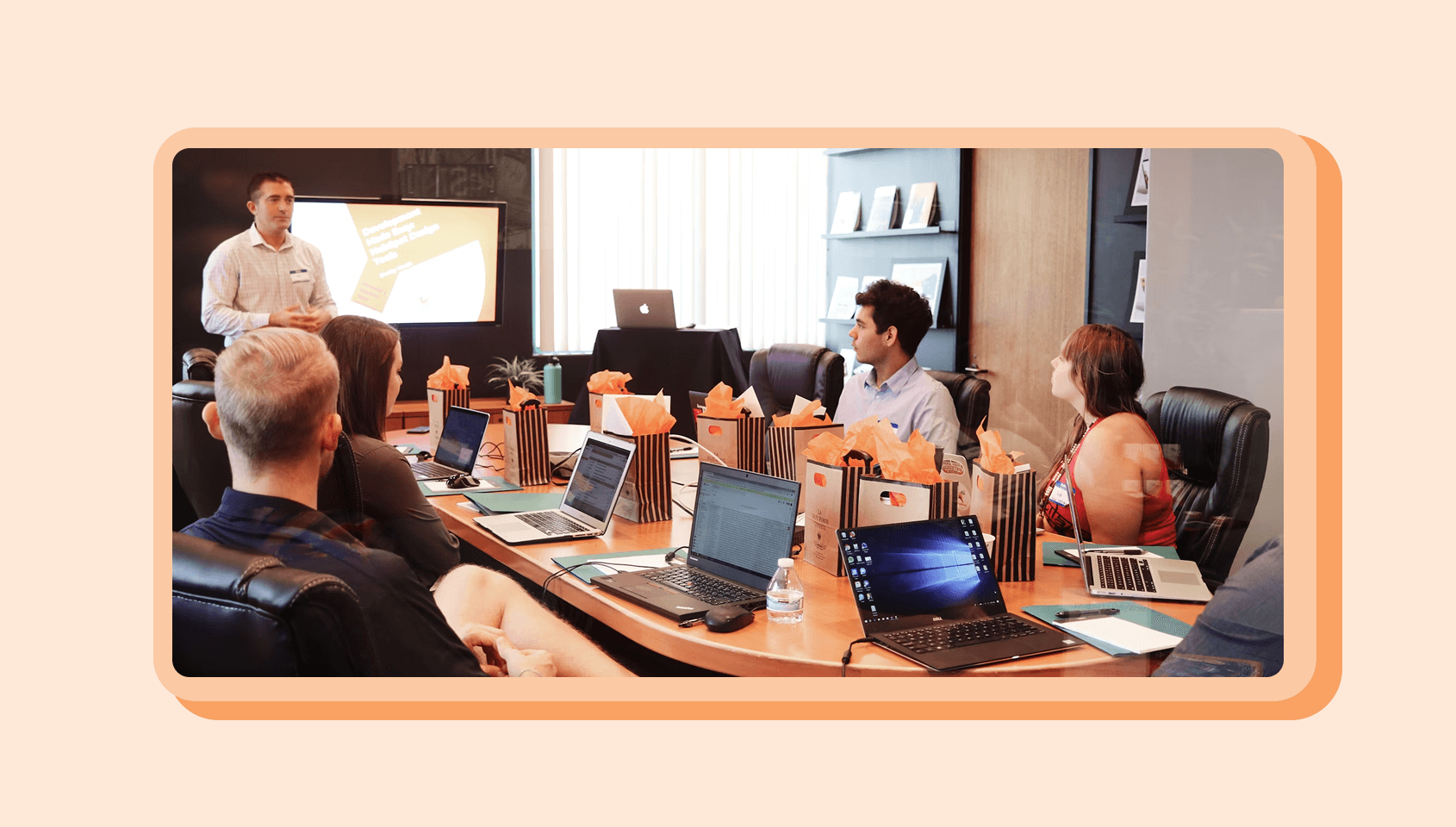 A bunch of people sitting in a meeting room, listening to a presenter.