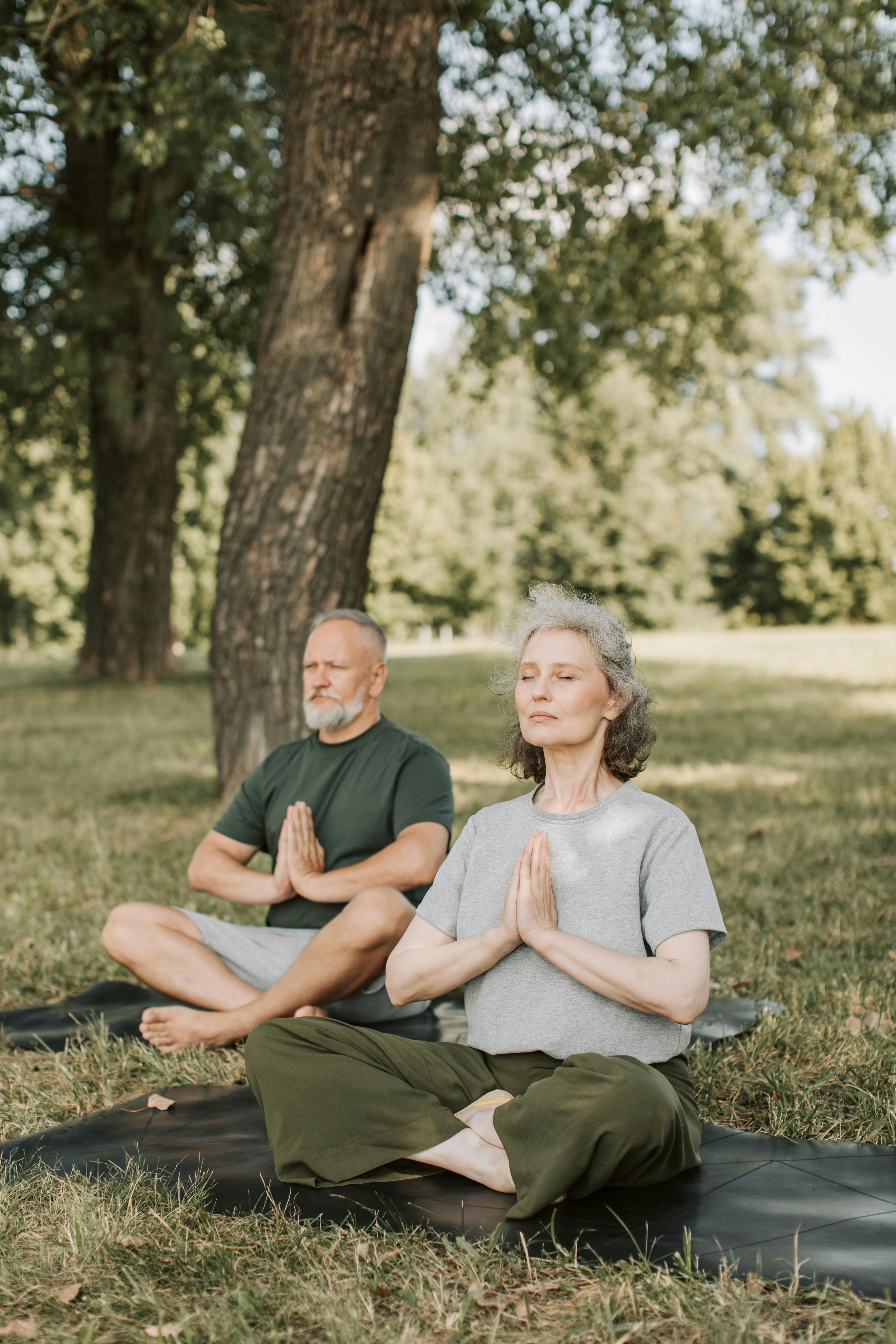 a woman sitting in a yoga position in a park